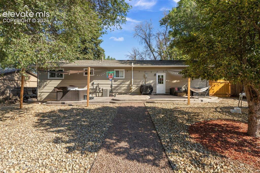 Image 27 of 30: Expansive backyard featuring a gravel path, mature trees, and a concrete pa
