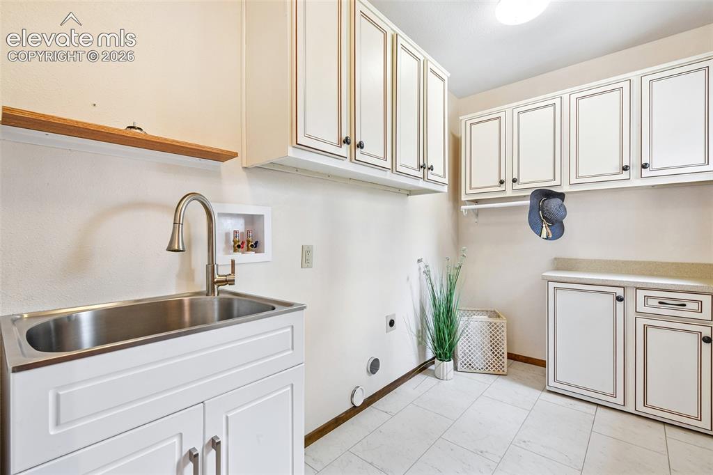 Image 15 of 49: Roomy laundry off kitchen, has cabinets and utility sink