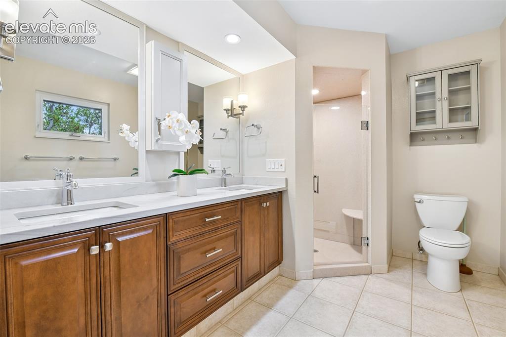 Image 20 of 49: Quartz counters and walk-in shower with seating