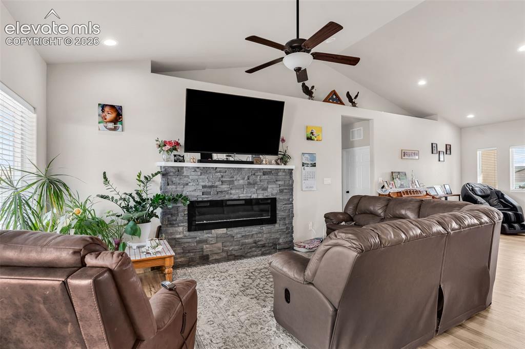 Image 10 of 49: Living area featuring a stone-clad fireplace with an integrated electric in