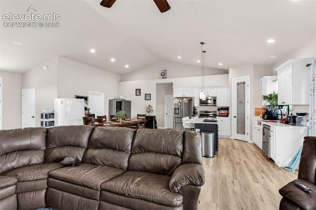 Image 11 of 49: Open-concept living area with vaulted ceilings and wood-finish flooring