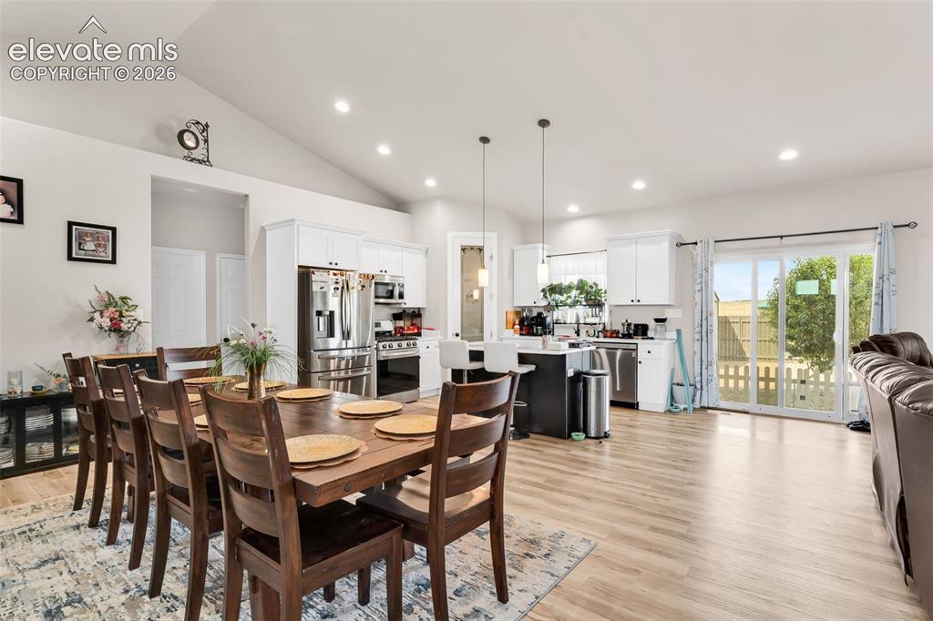 Image 12 of 49: Vaulted ceilings over an open-concept living area with wood-finish flooring