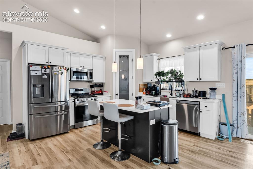 Image 15 of 49: Kitchen featuring wood-finish flooring, white cabinetry, and stainless stee