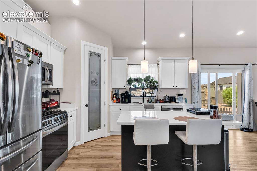 Image 16 of 49: Modern kitchen featuring white cabinetry, stainless steel appliances, a cen