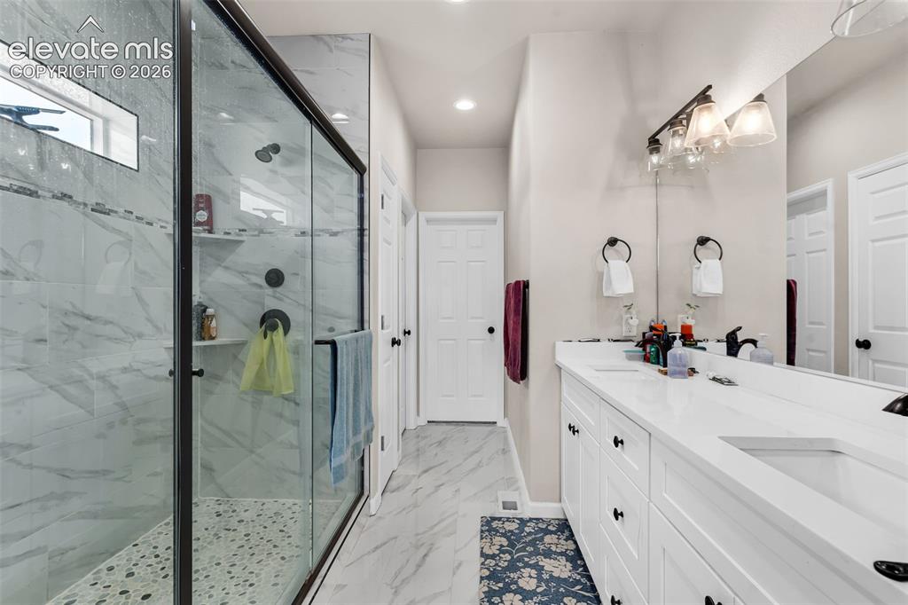 Image 20 of 49: Spacious bathroom featuring a frameless glass shower enclosure with a pebbl