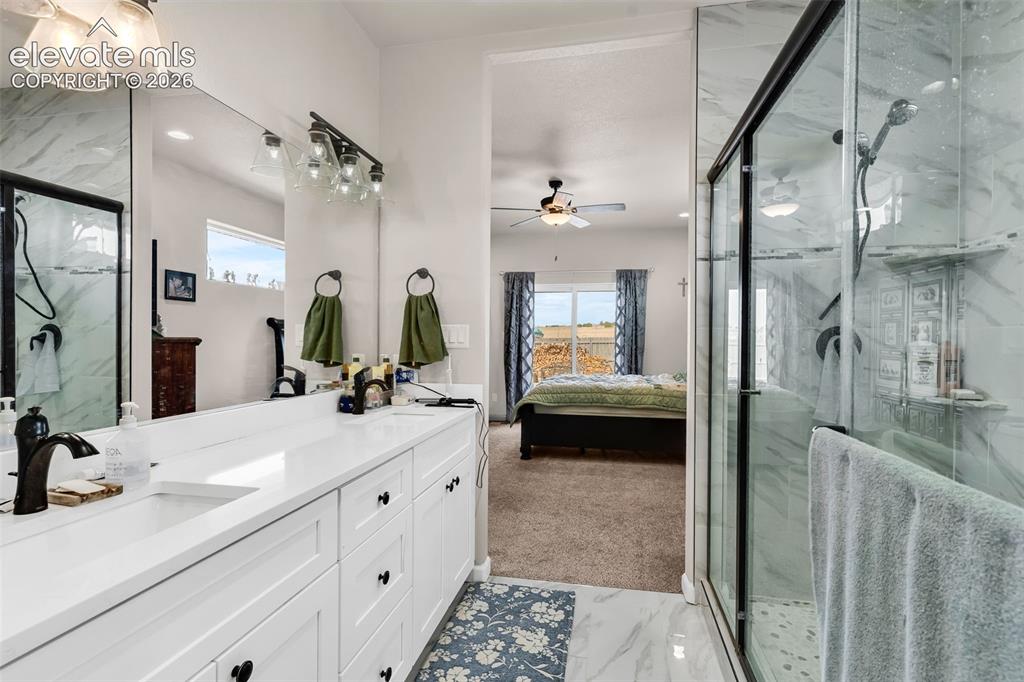 Image 21 of 49: Dual vanity with white cabinetry and integrated sinks, glass-enclosed showe