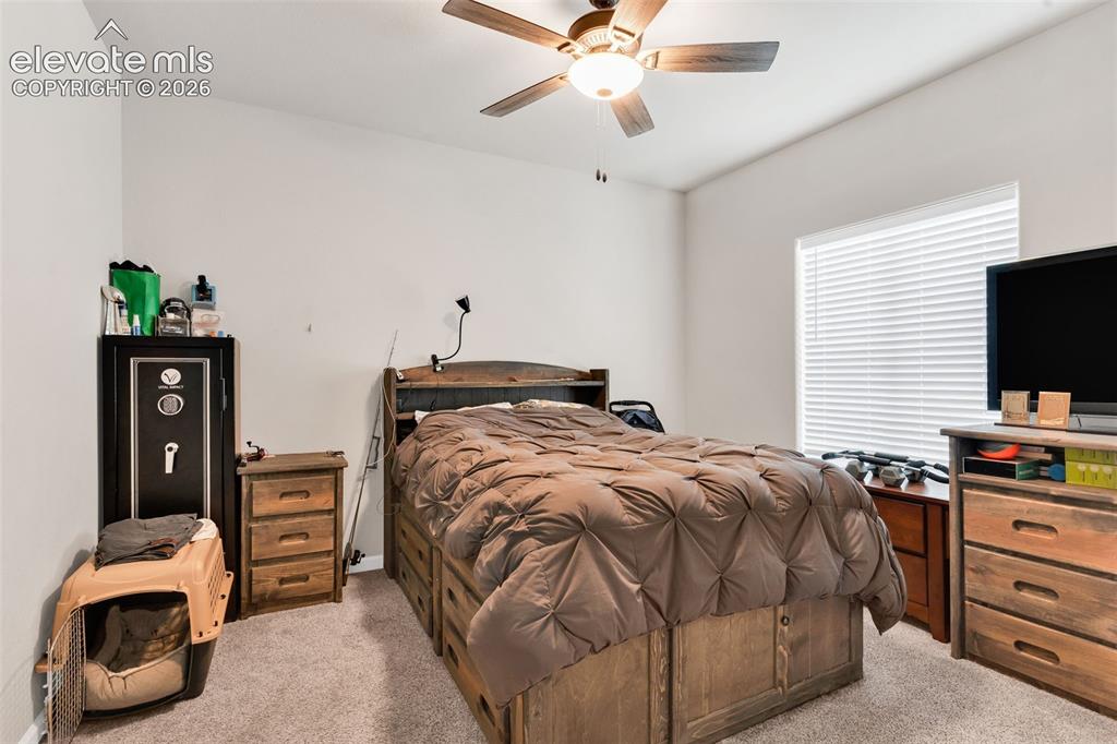 Image 23 of 49: Carpeted bedroom featuring a ceiling fan, window with blinds, and white pai