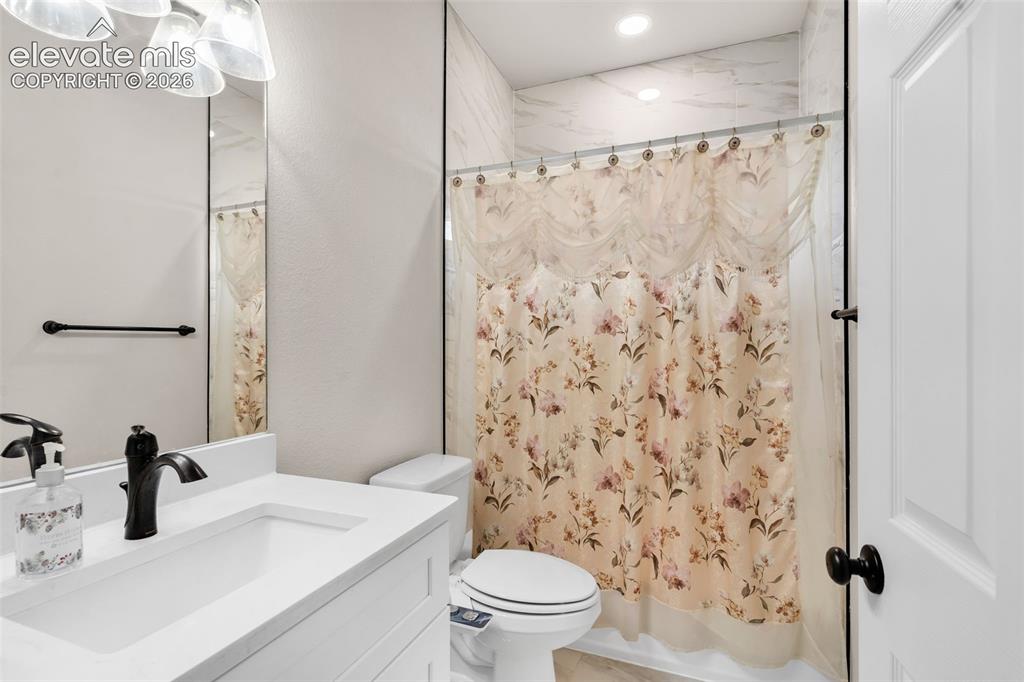 Image 24 of 49: White vanity with an integrated sink, black faucet, and white countertop