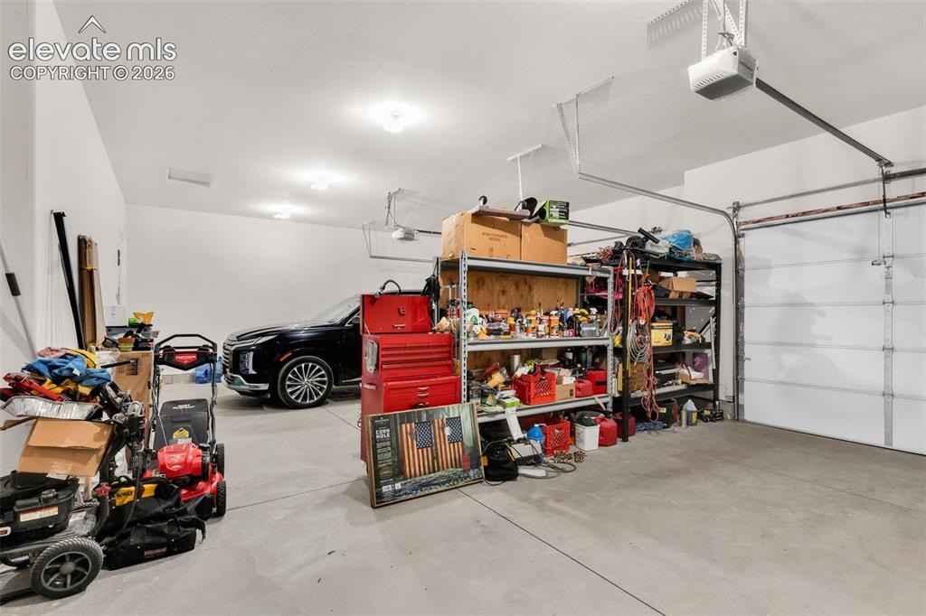 Image 29 of 49: Spacious garage with light grey concrete flooring and white painted walls
