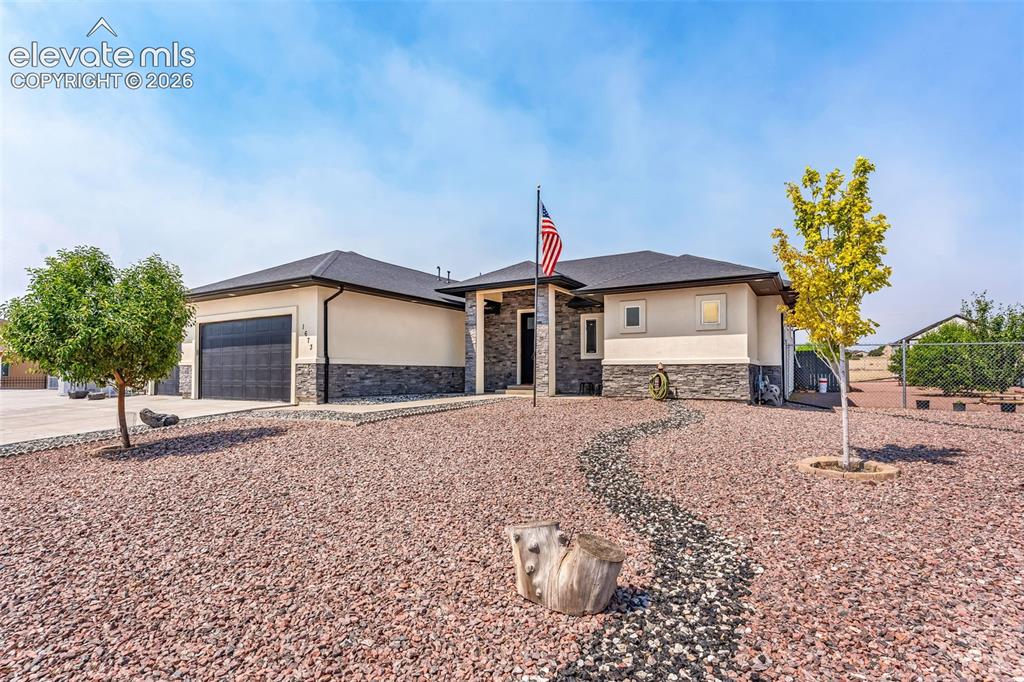 Image 3 of 49: Contemporary single-story residence featuring a stucco exterior with stone