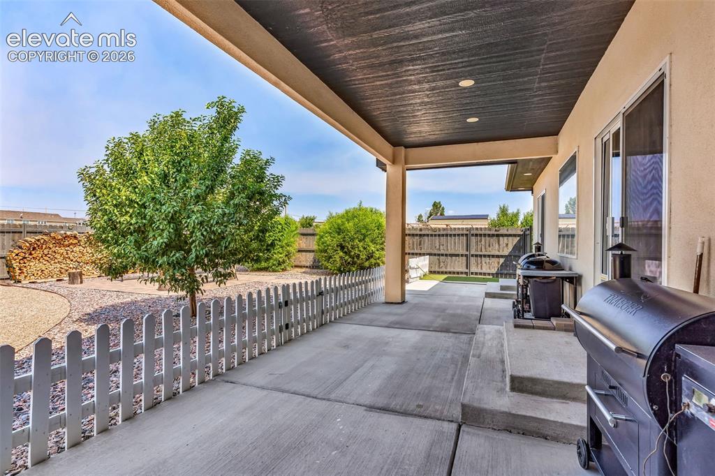 Image 32 of 49: Covered concrete patio with recessed lighting, stucco exterior, and sliding