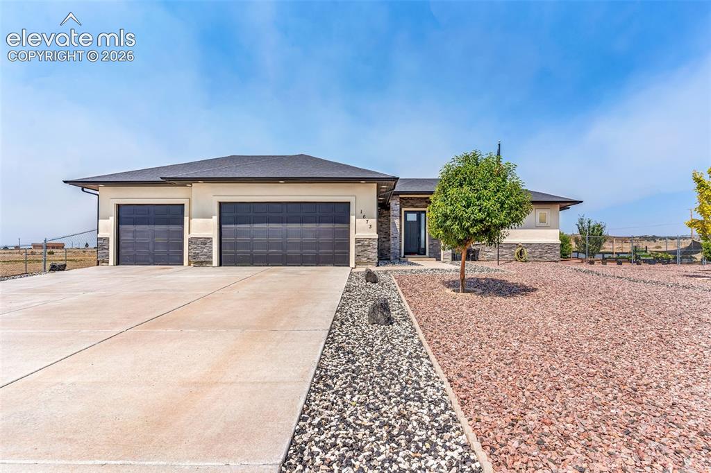Image 4 of 49: Contemporary stucco exterior with a dark shingle roof and stone accents