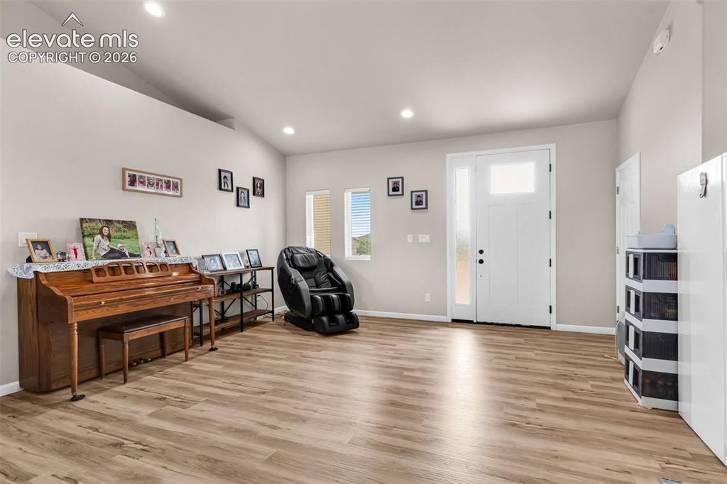 Image 6 of 49: Entry foyer with woo-finish flooring, recessed lighting, and vaulted ceilin