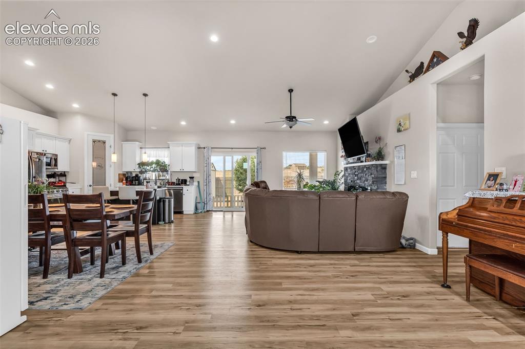 Image 7 of 49: Spacious open-concept living area featuring wood-finish flooring and vaulte