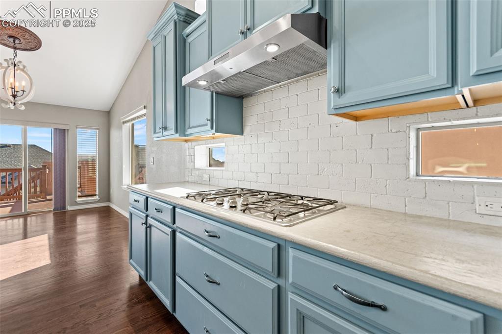 Image 10 of 45: Kitchen with blue cabinets, tasteful backsplash, under cabinet range hood, 