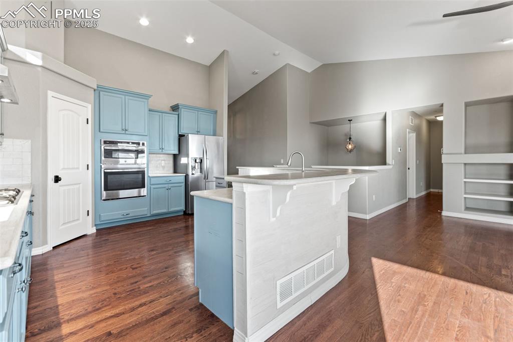 Image 11 of 45: Kitchen featuring decorative backsplash, blue cabinets, appliances with sta