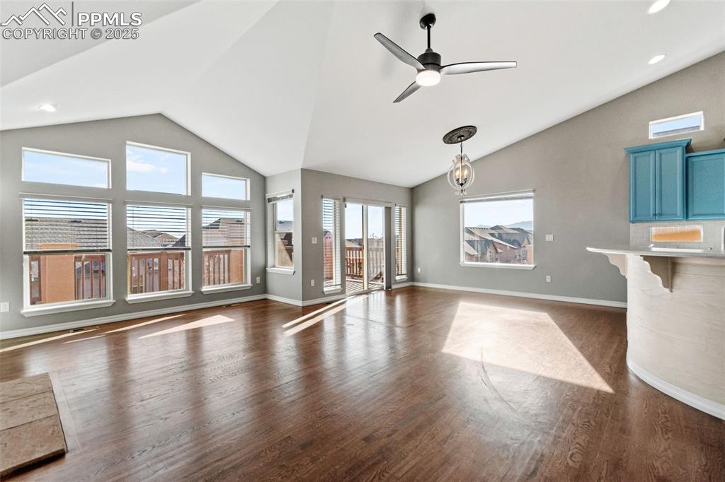 Image 16 of 45: Unfurnished living room with dark wood-style floors, a ceiling fan, and hig