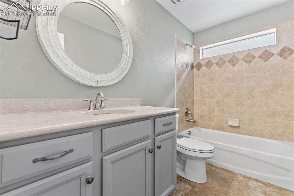 Image 17 of 45: Bathroom featuring shower / bath combination, vanity, a textured wall, and 