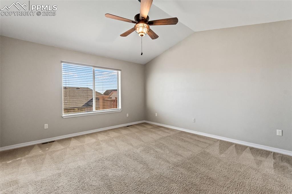 Image 24 of 45: Spare room featuring vaulted ceiling, light carpet, and ceiling fan