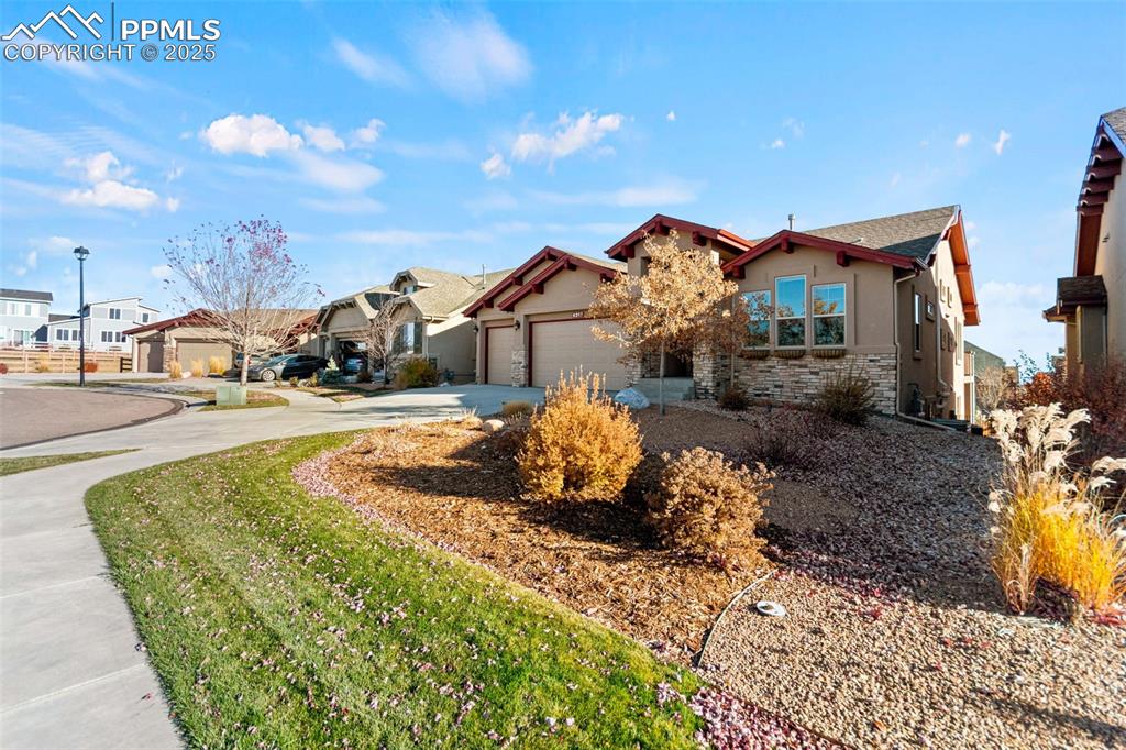 Image 3 of 45: View of front of house with stucco siding, stone siding, concrete driveway,