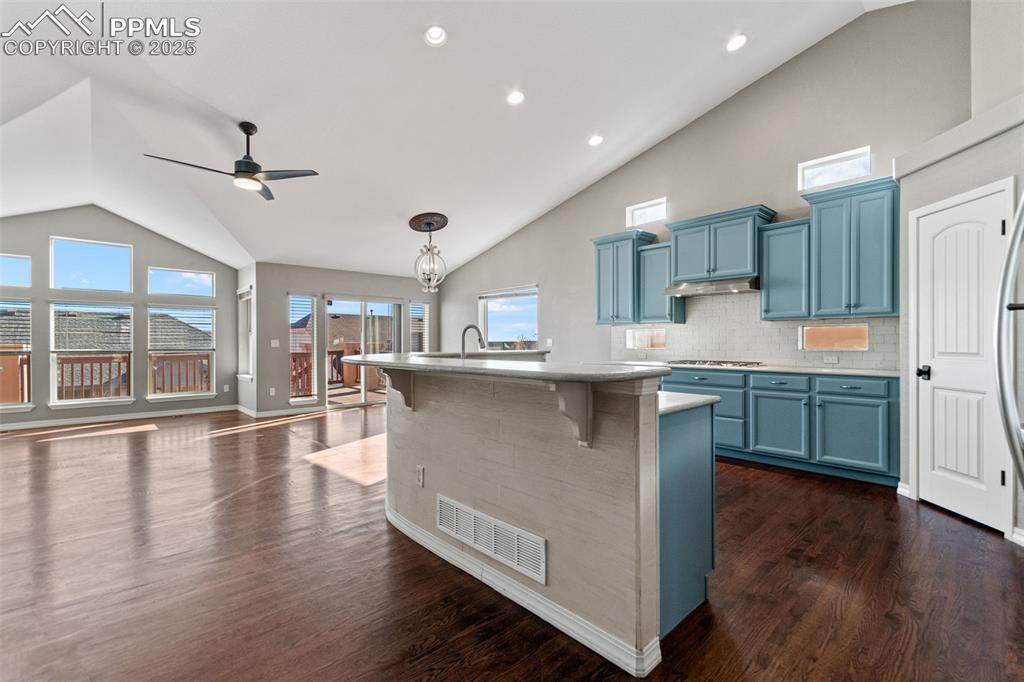 Image 4 of 45: Kitchen with blue cabinetry, tasteful backsplash, high vaulted ceiling, a k