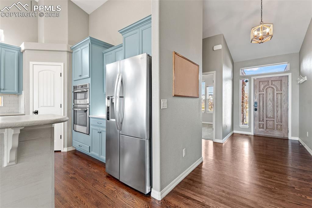 Image 5 of 45: Entrance foyer with dark wood finished floors, a chandelier, and high vault