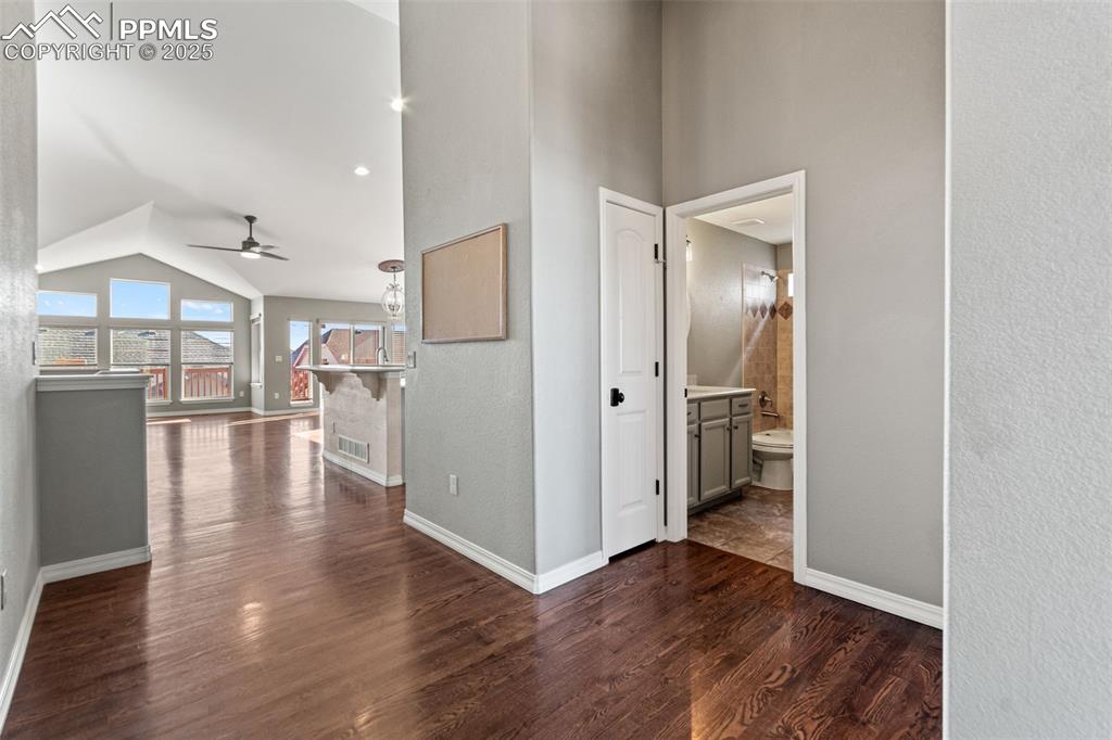 Image 6 of 45: Hall with dark wood-style flooring, high vaulted ceiling, and a textured wa