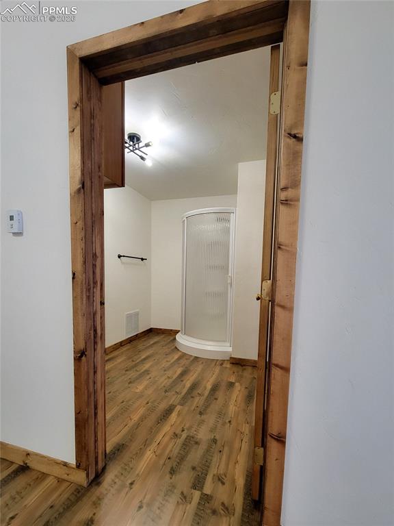 Image 13 of 43: The bathroom features laminate wood flooring with a corner shower enclosure