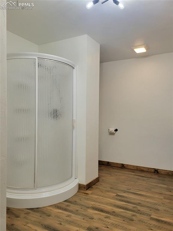 Image 15 of 43: Bathroom featuring a curved glass shower enclosure, wood-look flooring, and