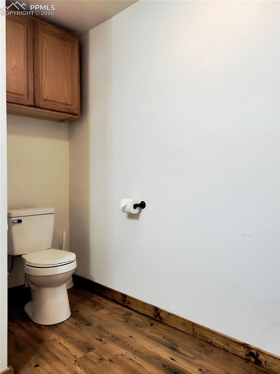Image 19 of 42: Bathroom with wood flooring, white walls, and wood cabinets