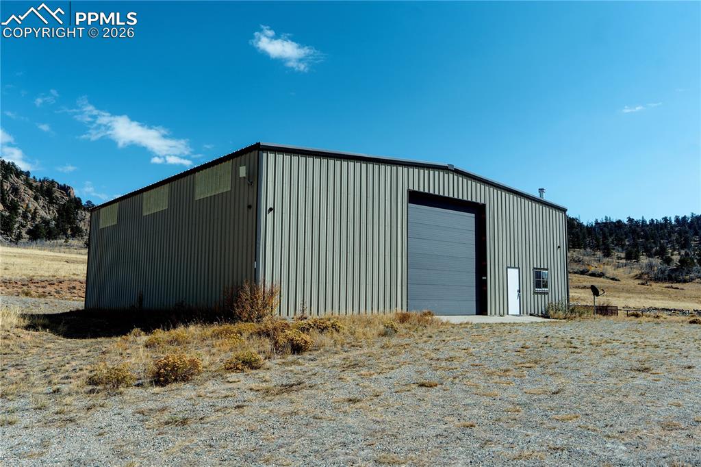 Image 2 of 43: This property features a large metal building with a roll-up garage door an