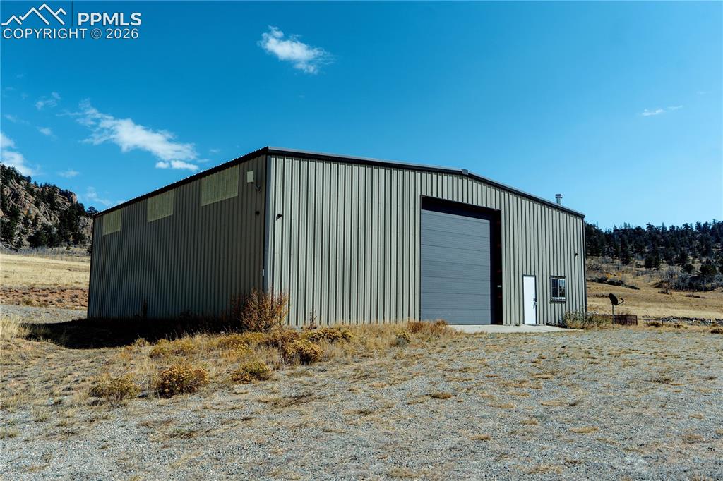 Image 2 of 42: This property features a large metal building with a roll-up garage door an