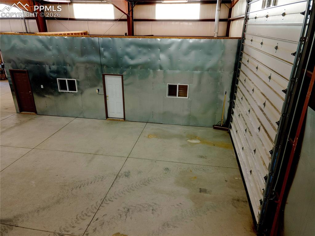 Image 21 of 42: The property features a spacious interior with concrete flooring and expose
