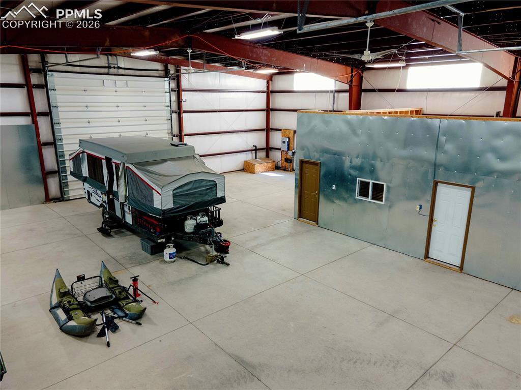 Image 23 of 42: Spacious warehouse interior featuring a large roll-up door, exposed metal b