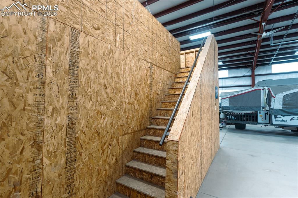 Image 27 of 43: Interior staircase featuring wood paneling and a metal handrail