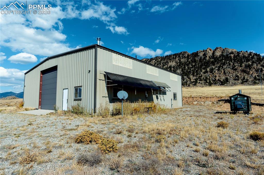 Image 3 of 42: The property features a large metal structure with a roll-up door, a standa
