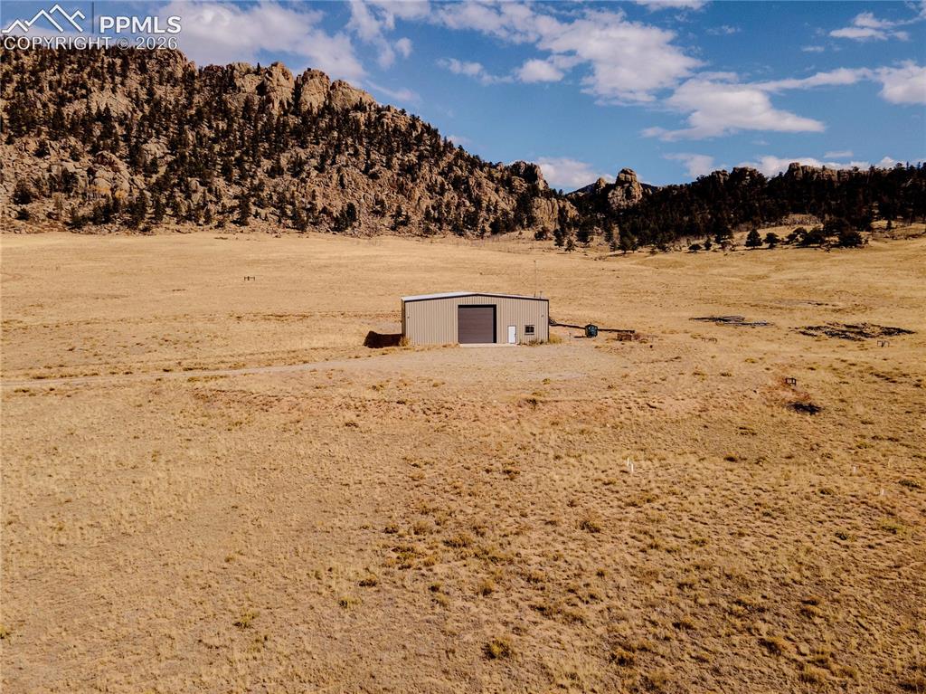 Image 40 of 42: The property features a large metal structure with a roll-up door, situated