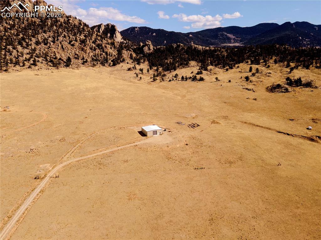 Image 41 of 43: Expansive property featuring a detached building, a winding dirt road, and 