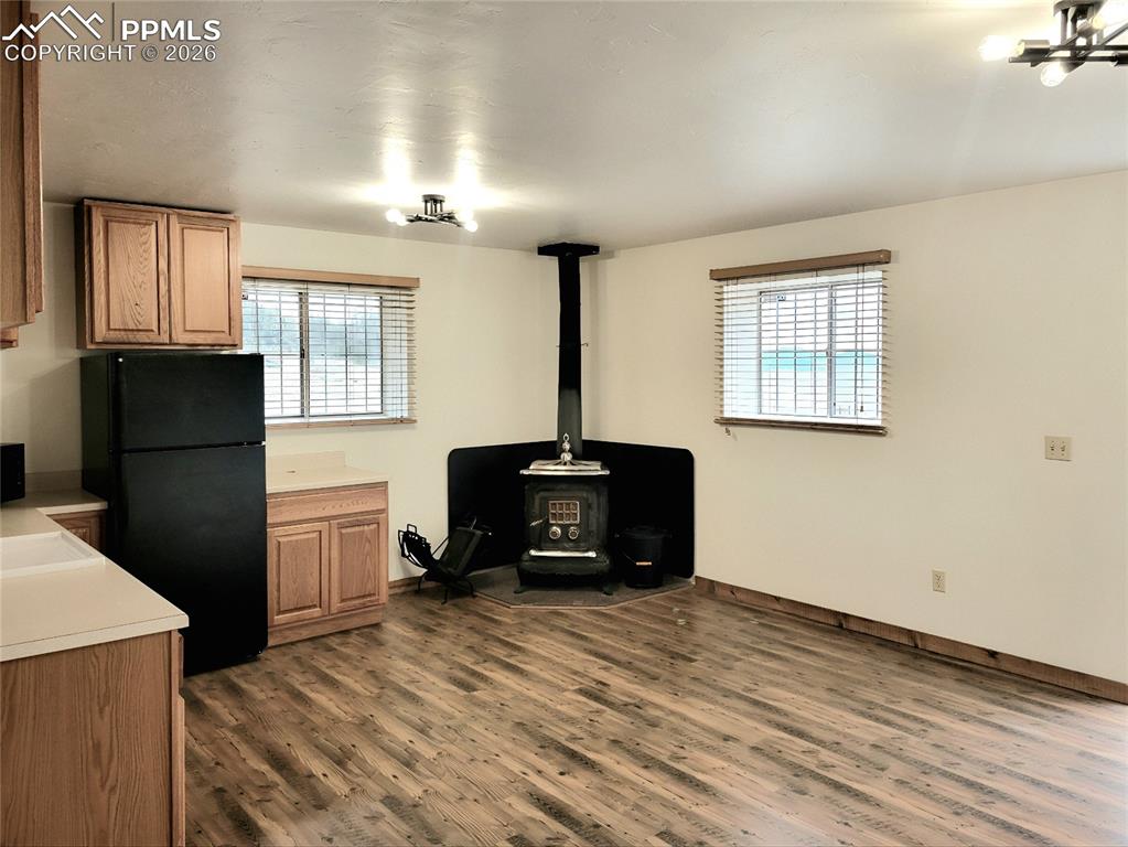 Image 9 of 43: The property features a wood stove, laminate wood flooring, kitchen cabinet