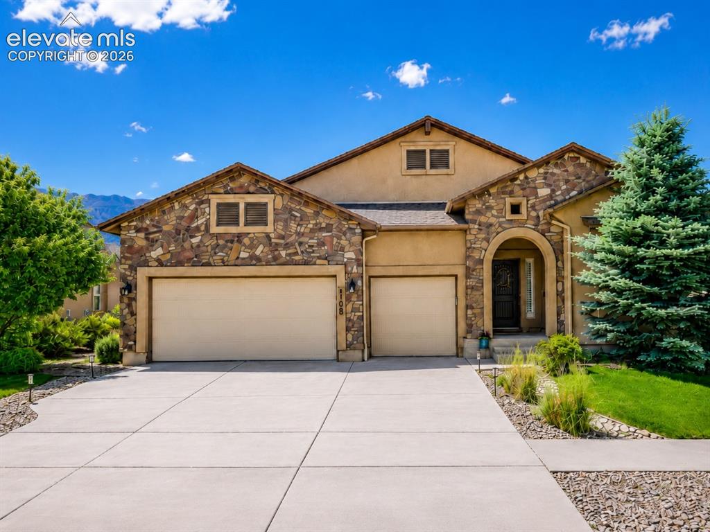 Image 1 of 46: Stone and stucco exterior detailing a two-car garage, arched entry, and con