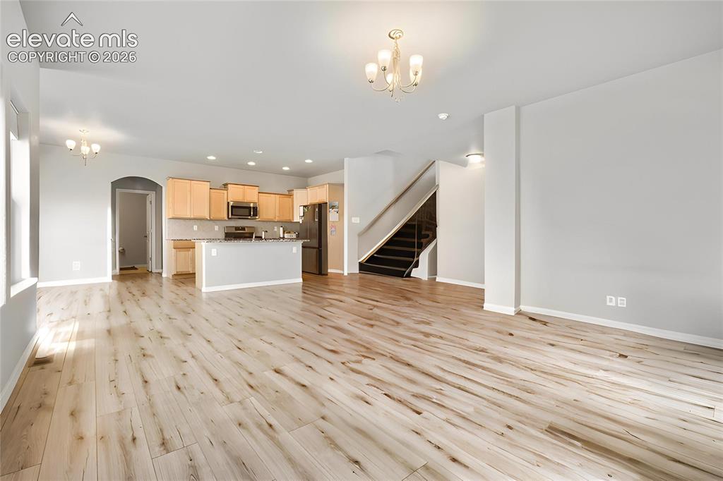 Image 10 of 33: Expansive living area featuring light wood-finish flooring, a kitchen with