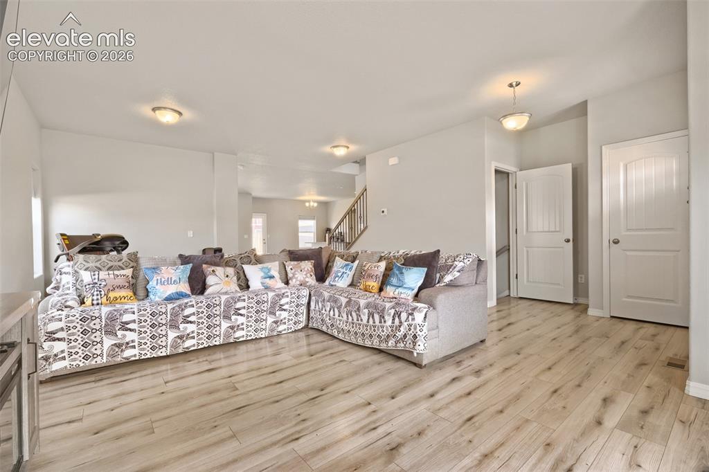 Image 11 of 32: Open-concept living area featuring wood-finish flooring, a kitchen with lig