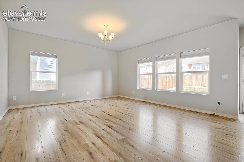 Image 12 of 33: Spacious room featuring wood-finish flooring, vaulted ceilings, and a five-