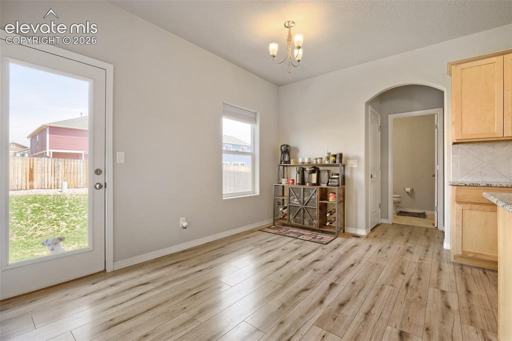 Image 14 of 33: Light wood-finish flooring throughout, featuring a full-light patio door op