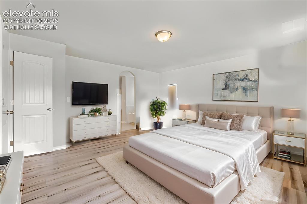 Image 16 of 33: Virtually Staged Spacious room featuring light wood-finish flooring, an arc
