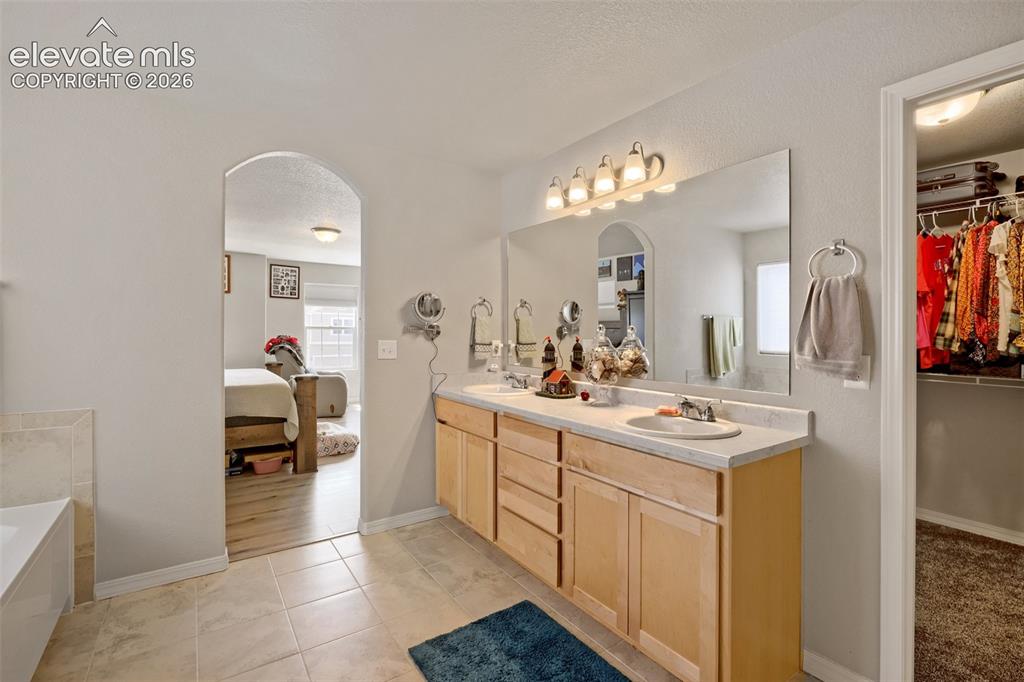 Image 17 of 33: Dual vanity with light wood cabinetry and a large wall-mounted mirror