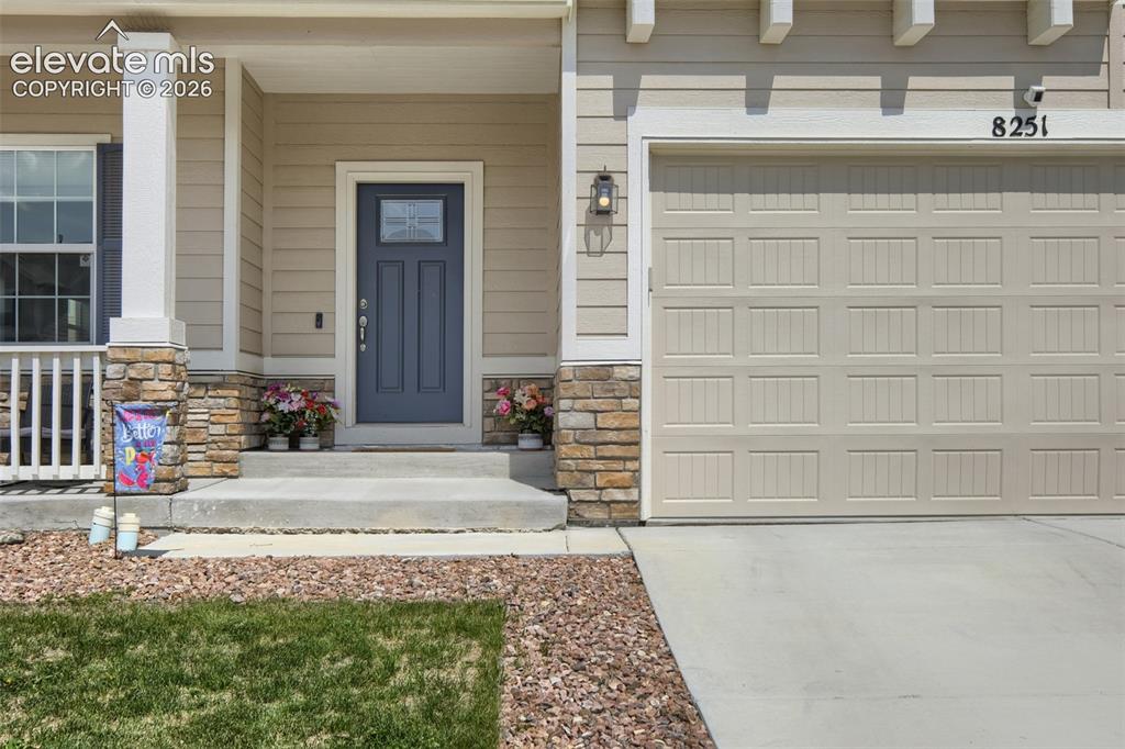 Image 2 of 33: Exterior facade featuring beige siding, stone accents, a paneled garage doo