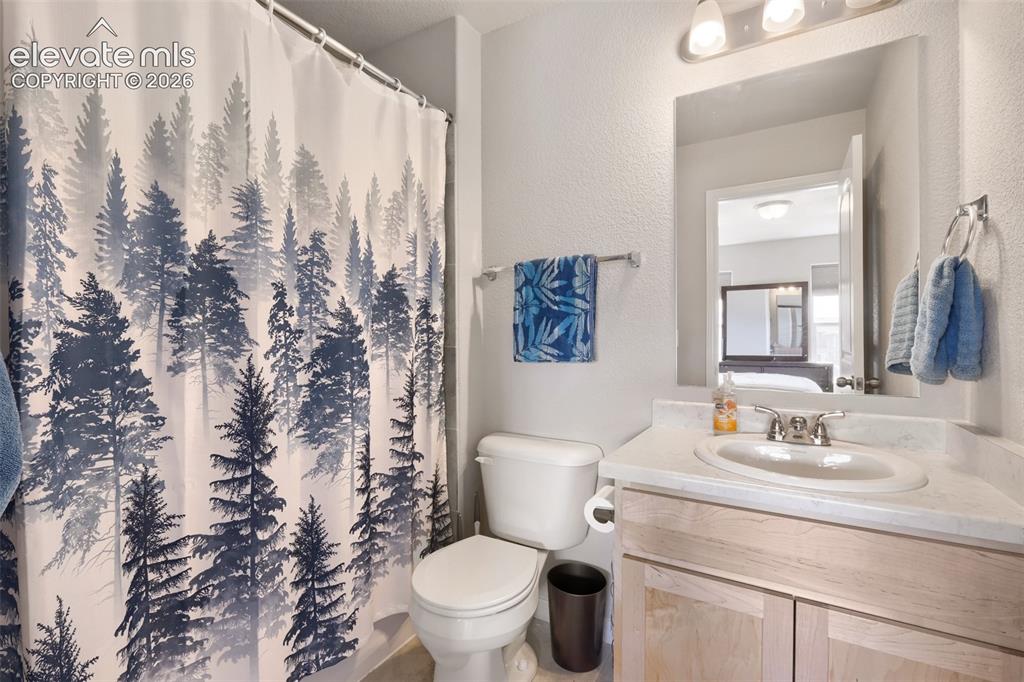Image 23 of 33: Bathroom featuring a single-sink vanity with light wood-finish cabinetry an