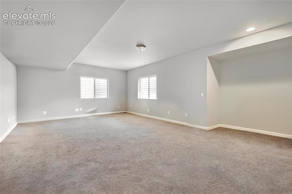 Image 24 of 33: Spacious interior room featuring neutral gray carpeting and light gray wall