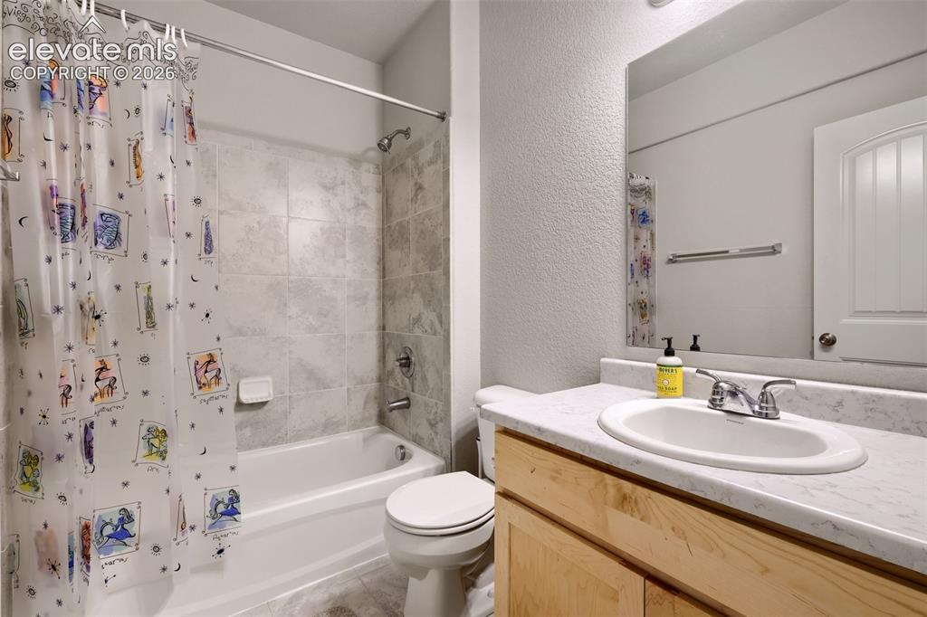 Image 27 of 33: Tub and shower combination with light-toned tile surround, single vanity wi